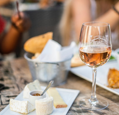 glass of wine and cheese, dips and bread on a ceramic plate 